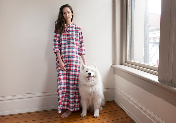 Girl wearing red and blue flannel long sleeve sleepshirt with fluffy dog