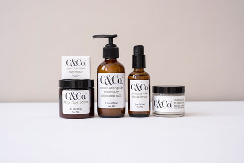 Five facial care products grouped in front of a two-toned back ground of grey and white