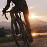 Man riding a road bike while the sun sets.