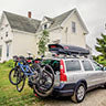 A car loaded with bikes on a Yakima bike rack sits in front of a house.