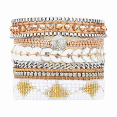 Gold Attica. Chunky Cuff bracelet made of layers of white and gold beaded strap, silver beads, coins, pavé ball, and chains, with gold crystals on a tan cord