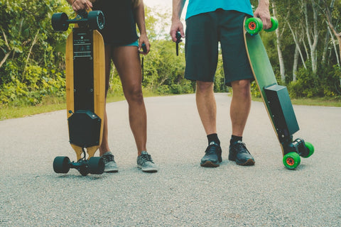 two men holding electric skateboards