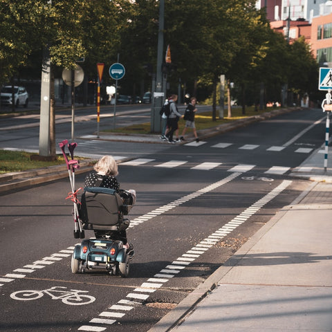 elderly woman riding an electric mobility scooter in the street
