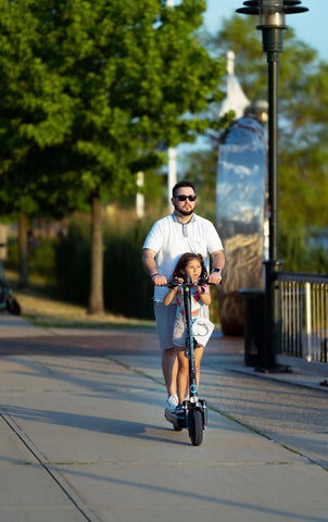 father and daughter riding electric scooter