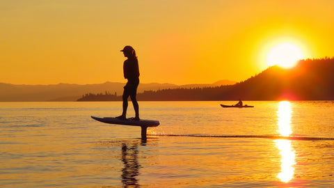 woman riding electric foil board in sunset