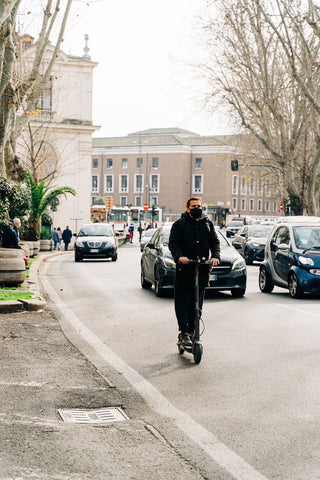 man with black mask riding electric scooter