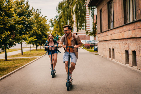 Man and woman laughing while riding electric scooter