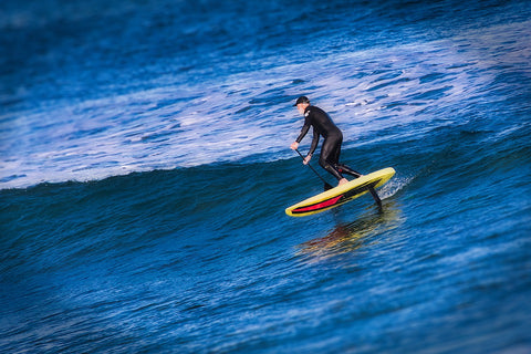 man riding electric foil board in the waves