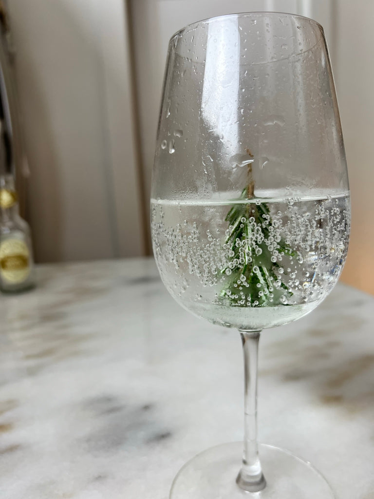 Wine glass with gin and tonic inside with a christmas tree standing to look like a snow globe gin and tonic