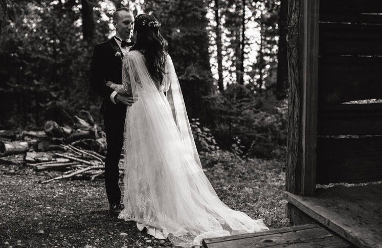 Peony Rice Bride Caitlin wearing abespoke wedding gown and a tulle cape adorned with pearls in the forest 