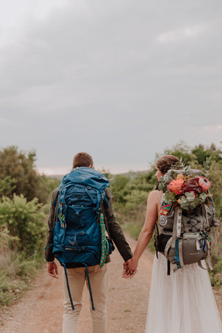 couple with hiking bags walking on a dirt road