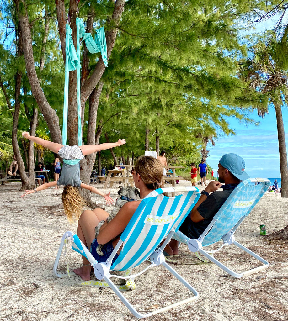 Family sitting in their SUNFLOW chairs and watching a performer on the beach