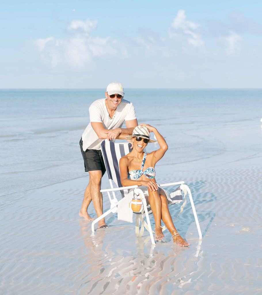 Leslie sitting on the beach in Key West with Greg standing behind her.