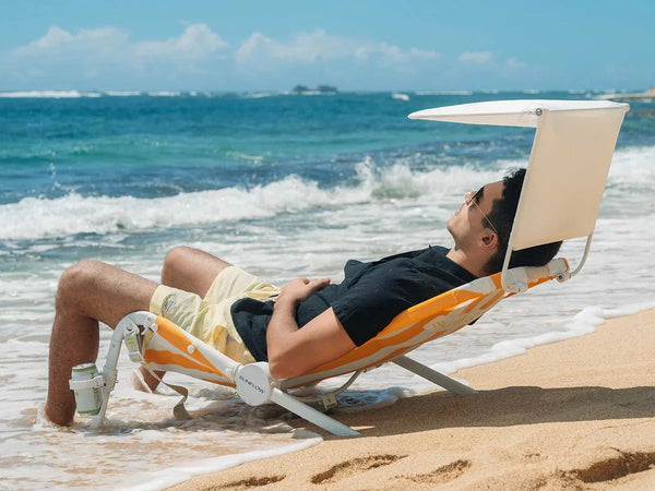 man reclining in a sunshine stripe SUNFLOW beach bundle at the beach