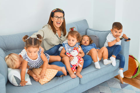 a woman and group of toddlers sitting on the sofa