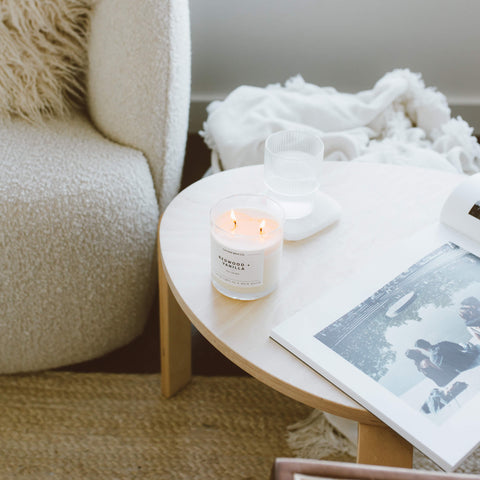 redwood vanilla candle on a table next to a couch