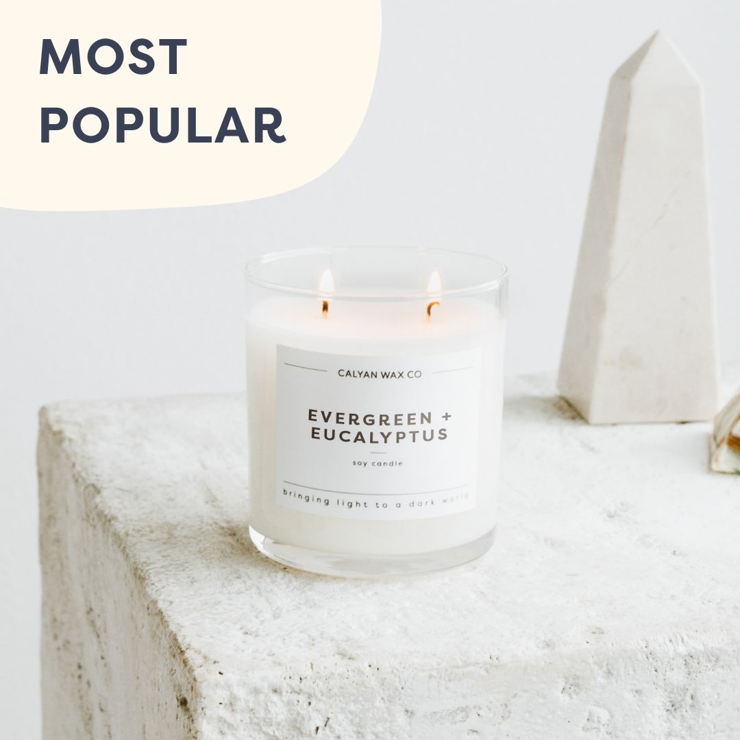 Evergreen + Eucalyptus soy wax candle burning on a beautiful concrete side table