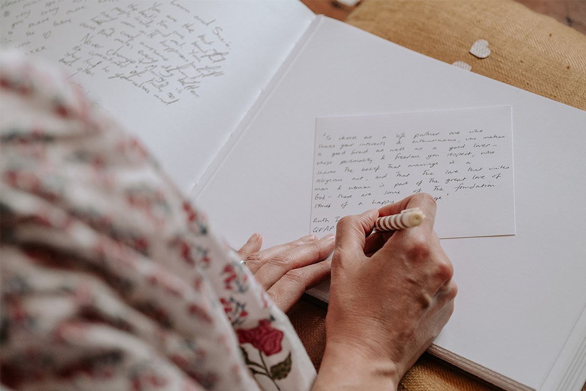 Wedding Guest writes in the scrap book, a hand crafted book from bound by hand