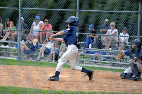 boy batting baseball near catcher beside gray fence