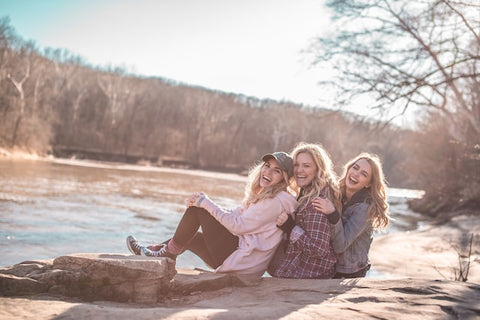 Three friends sitting by a lake