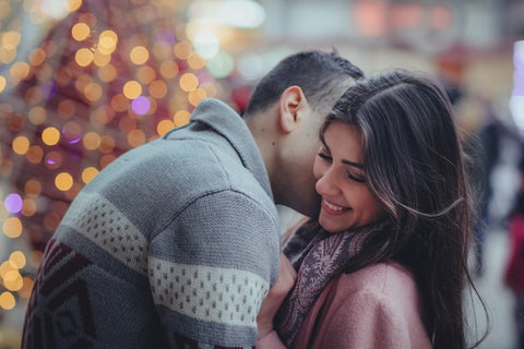 man kissing woman on a Christmas lights background