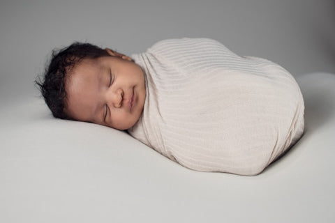 baby in white knit sweater lying on bed