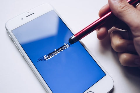 Phone with facebook app open being stroked by a pen
