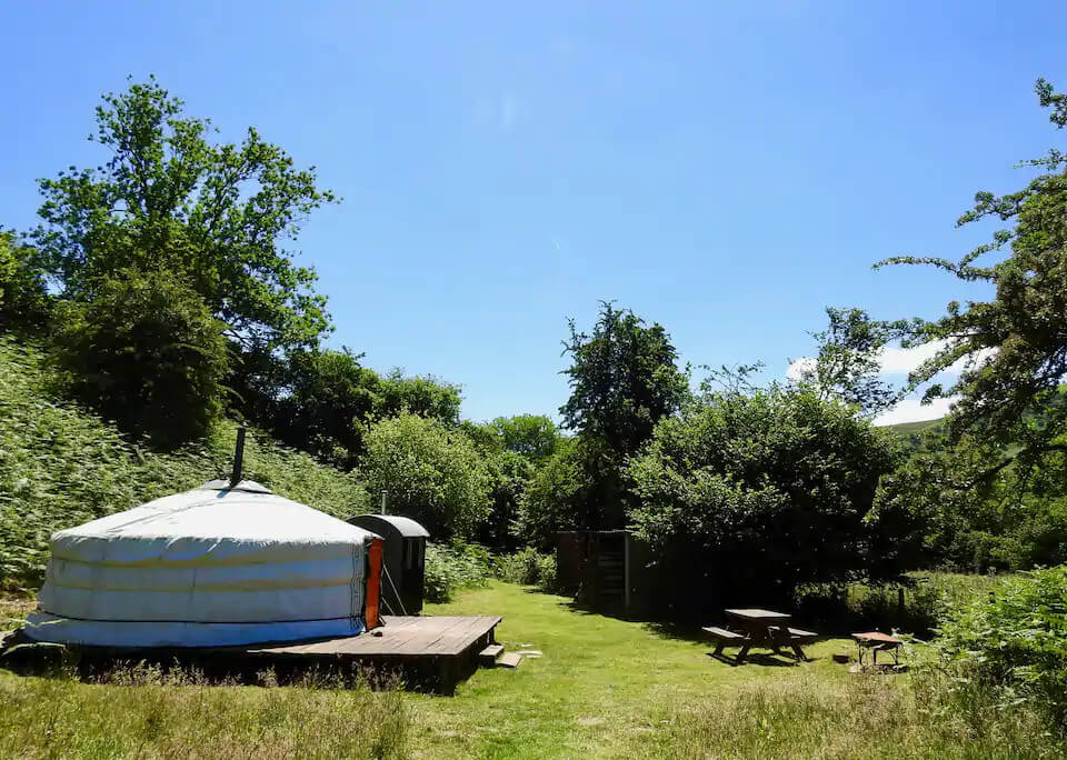 Eco retreats - Sustainable holiday accommodation - Moonlight Yurt in the middle of a green field with blue sky