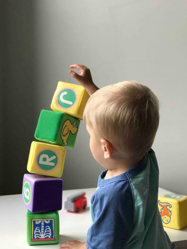 Toddler playing with to sustainable wooden blocks