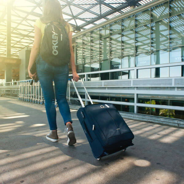 woman-walking-on-pathway-while-strolling-luggage