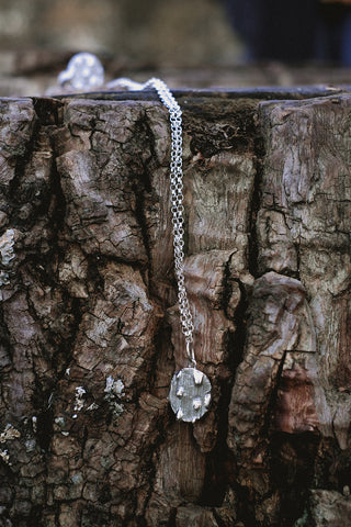 Close up of glacier jewellery melting on logs, contemporary silver necklaces with enamel, all handmade