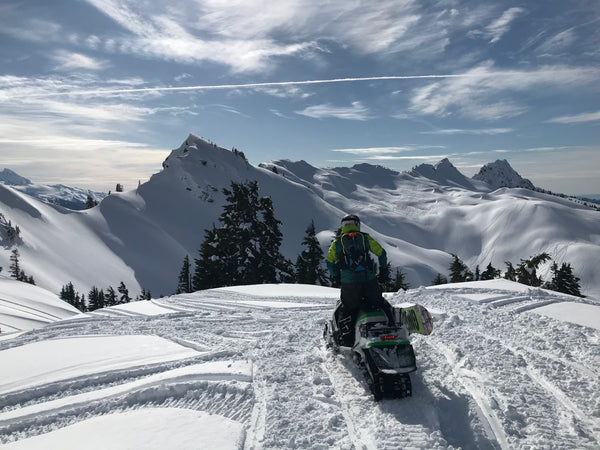 Snowboarding from a Snowmobile from mountain top with arctic cat