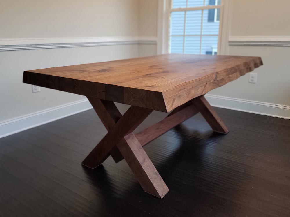 A thick custom live edge table with X-shaped wooden table legs.