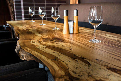 A close up of a live edge table top with wine glasses.