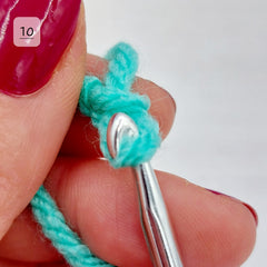 Pull the loop though the slip knot. You will need to angle the hook slightly to ensure the full strand pulls through without it splitting. Take care not to catch any of the yarn from the slip knot.  If it's hard to pull through, gently loosen the slip knot a little.