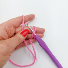 Step 3 - Insert your crochet hook underneath the two loops which are around your fingers. Use your thumb to hold the wool leading to the ball. You will feel a little like an octopus, until you get used to holding everything in place!