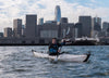 Man kayaking on the sea surrounded by skyscrapers