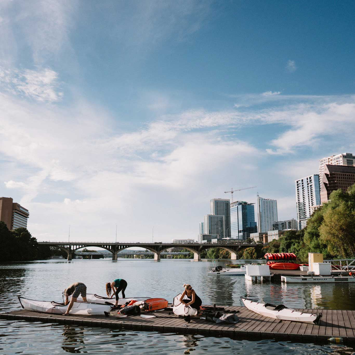 People on the deck by the river, assembling their bay st kayaks