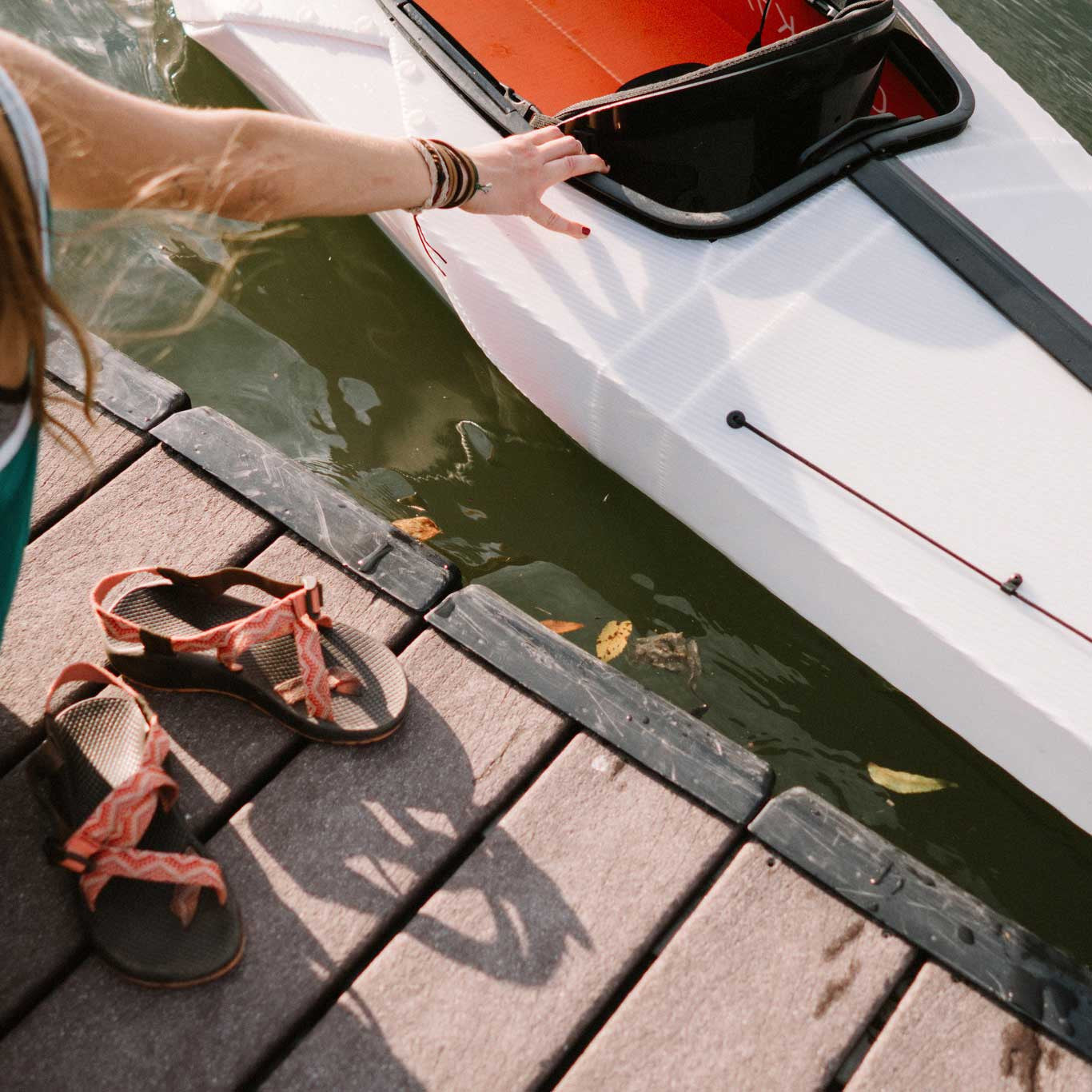 Close up showing the side of bay st in the water and a pair of sandals on the deck. 