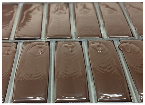Liquid dark chocolate being poured into molds, Coracao Chocolate Factory, Richmond CA.