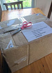 Cardboard box on my dining room table with 1 felted hat for BeanieFest in Australia - ready to go to the post office.
