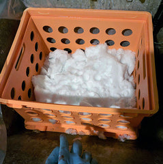 Snow piled up on pre-treated fabric in my basement sink. The orange milk crate is serving as a sieve to raise the fabric above the meltwater.