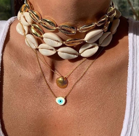 an example on how you can layer our natural white cowrie shell necklaces with other cowrie gold plated necklaces also available on our website and some simple gold necklaces with evil eye charm pendants.  