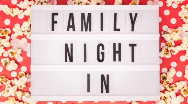 photo of a white sign that says "family night in" with popcorn all around it