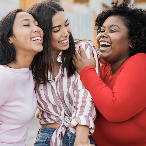 three women laughing together - two are thin and one is curvy - all are happy