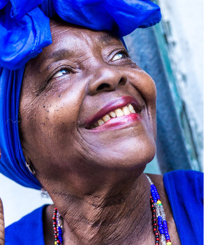 older black woman with blue headscarf and red lipstick, smiling