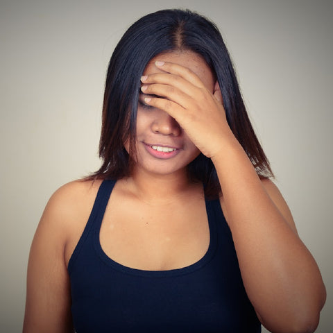 asian woman with black hair and blank tank top hiding her face looking rueful