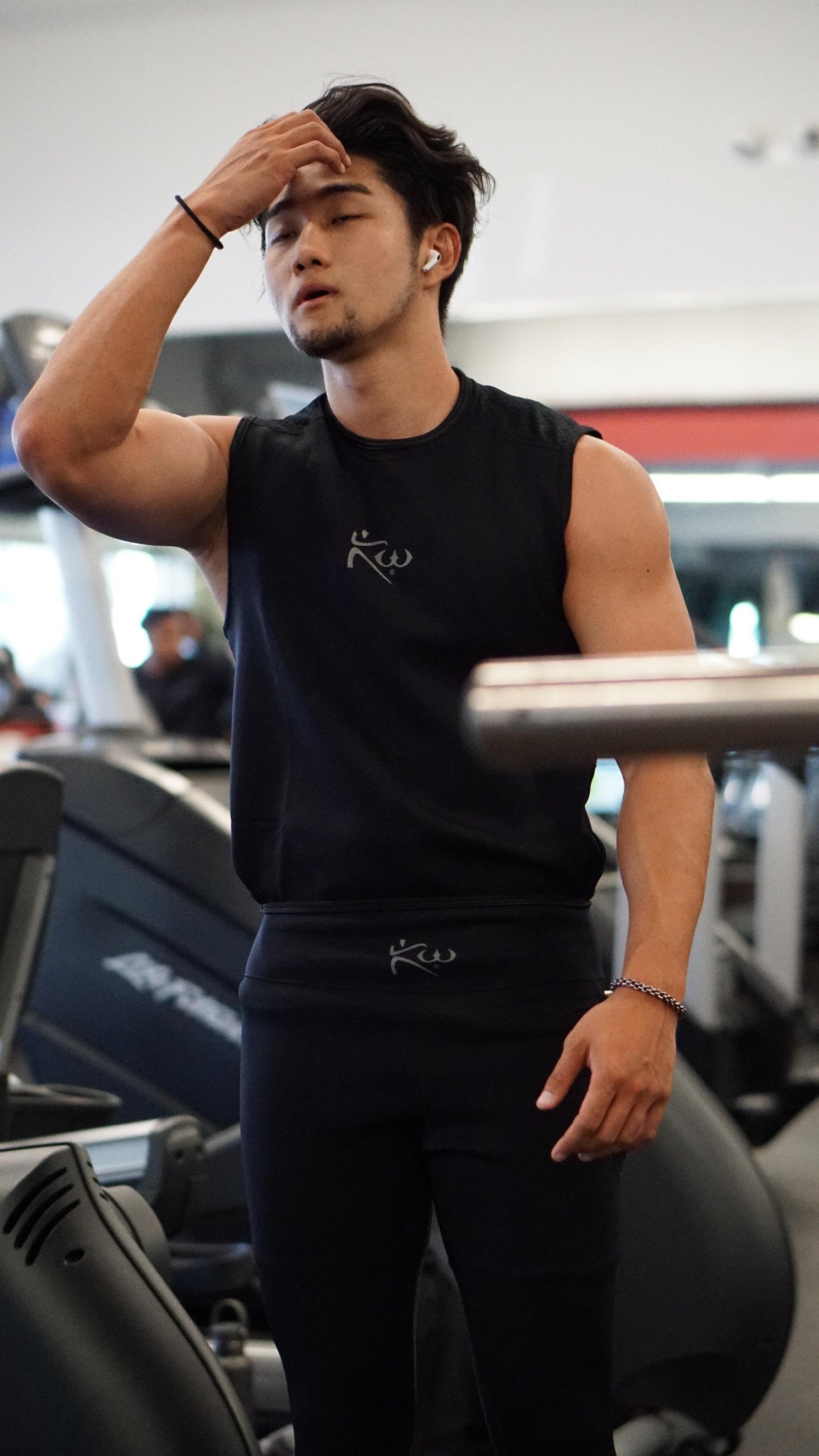 Man wiping brow in a gym wearing a black Kutting Weight neoprene sauna suit