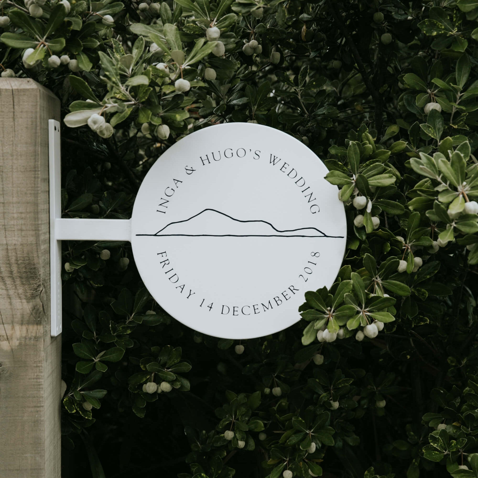 A white metal round sign displaying a wedding welcome sign