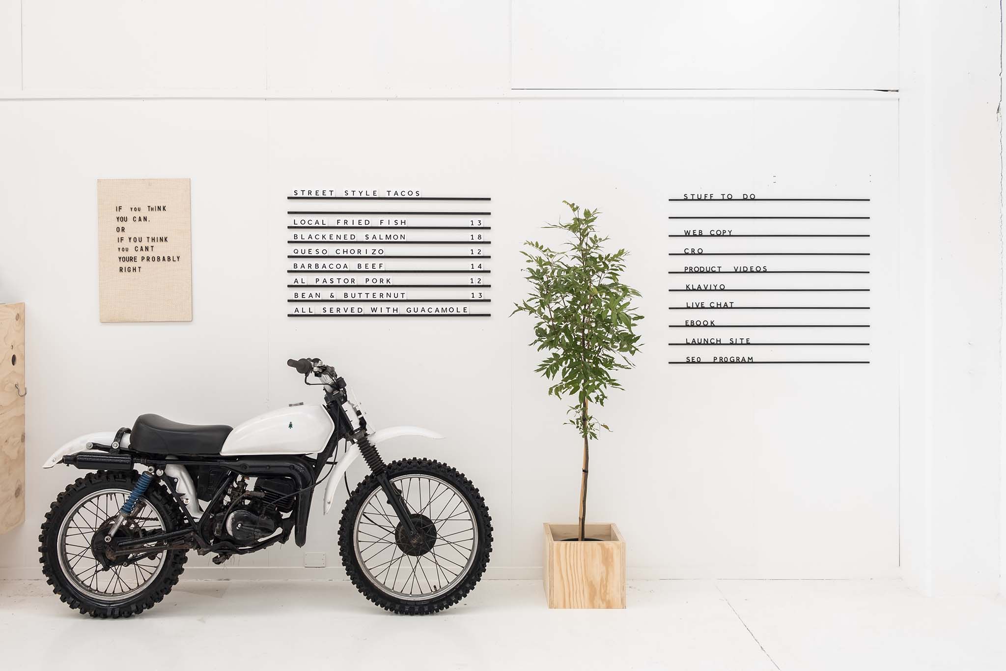 cafe menu board on white wall with motorbike next to it minimalistic office interior design